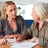 Elderly woman discussing benefits with business woman